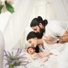 A serene and intimate portrait of new parents embracing their sleeping newborn. This light and airy style, set against a clean white backdrop, highlights the pure, peaceful connection of a new family.