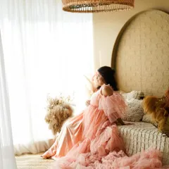 A dreamy portrait of a mother-to-be in a magnificent pink tulle gown, creating a soft and romantic scene.