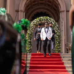The groom's grand entrance, looking sharp in a white tuxedo as he walks down the red carpet. A moment of style and anticipation.