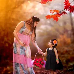 A pregnant mother and her young daughter hold hands in a beautiful, autumn-colored forest. This is a warm and loving portrait that celebrates the bond between them before the new baby arrives.
