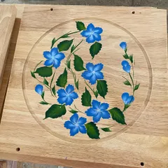 A finished wooden panel featuring delicate blue flowers, ready to be installed as part of the larger ceiling design.