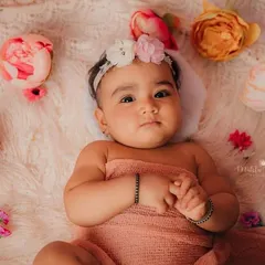 This pretty 8-month-old is wrapped in a peach swaddle, surrounded by flowers. A beautiful, soft setup for a milestone shoot.