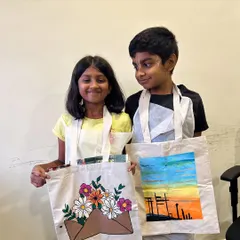 This brother and sister duo proudly display the tote bags they painted. It's a fun activity for siblings to do together, and they each get to show off their individual style.