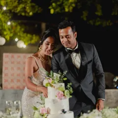 A couple cuts their elegant, multi-tiered wedding cake adorned with fresh flowers.