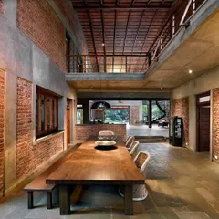 The dining area at The Mango House in Alibag is the heart of the home. Here, exposed brick walls, a double-height ceiling with terracotta tiles, and a large wooden table create a space that is both grand and grounded, perfect for conversations that last for hours.