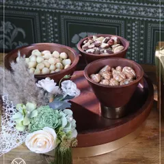 A beautifully arranged gourmet hamper. This wooden serving tray with assorted nuts is paired with a delicate floral arrangement, showing how I combine edible treats with lasting decor for a complete gift.