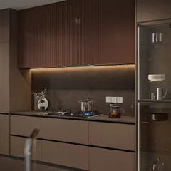 This angle highlights the seamless integration of the glass crockery unit and the cooking hob. The handleless drawers maintain a clean, uninterrupted flow across the lower cabinets.