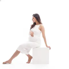 A simple and modern pose using a white block, this shot highlights the beautiful silhouette of pregnancy. The clean, minimalist background keeps the focus entirely on the mother-to-be.