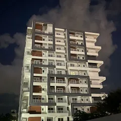 This is the view of a luxury apartment building I designed, seen here at night. The architectural design uses bold, geometric frames to create visual interest and highlight the private balconies, giving the structure a strong, modern identity.