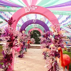 Step into a world of pure joy with an entrance that sets a vibrant tone. We design immersive experiences like this colorful arched walkway, using fabric draping and floral arrangements to build excitement from the very first moment.
