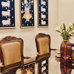 Sourcing the right art is like finding a hidden treasure. These traditional Pichwai paintings bring a story of devotion and culture to this dining space, perfectly complementing the classical carved chairs and creating a truly elegant atmosphere.