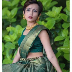 This outdoor portrait blends traditional and modern styles. The vibrant green of the silk saree stands out against the natural foliage, and the model's contemporary pixie cut adds a unique, edgy twist to the ethnic look.