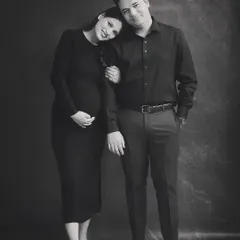A timeless black and white portrait of the expecting couple. The simplicity of the dark backdrop and matching outfits puts all the focus on their happy connection.