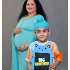 A proud "BIG BROTHER" poses with a cute sign in front of his expectant mother during their family maternity session in our studio.