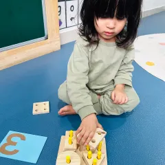 A young learner carefully places a shape into a puzzle. This simple act is building problem-solving skills, spatial awareness, and concentration, all through the power of play.