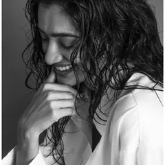 This black and white conversion of a studio shot emphasizes the texture of the model's wet hair and her joyful expression. Without color, the focus shifts entirely to the light, shadow, and the genuine emotion of the moment.