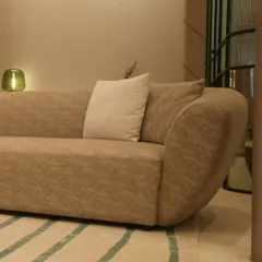 This custom sofa features a gently curved frame upholstered in a textured taupe fabric, creating a warm and inviting centerpiece. Paired with a simple off-white cushion, it showcases our ability to create comfortable, modern seating that is rich in texture.
