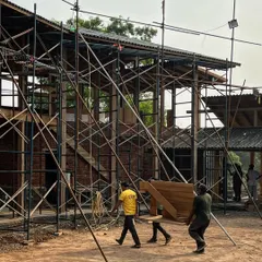 The staircase model being carried to its intended location within the farmhouse construction site. This allows us to see the model in context and make final adjustments before fabrication begins.