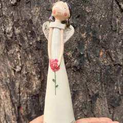 A close-up of my angel figurine, holding a single pink rose. The details, from the textured wings to the gentle expression, are all carefully crafted by hand.