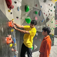 Learning to climb is a journey we take with you. Here, one of our instructors provides one-on-one guidance to a young climber, explaining the route and technique. Our introductory sessions focus on basics, balance, and having fun.