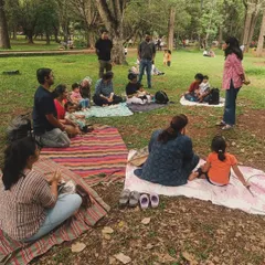 A wider view of our story circle under the trees. Families spread out on their mats, listening in. This image captures the scale of our community and the beautiful, natural setting of our weekend workshops.