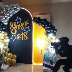 A personalized 18th birthday photo backdrop in black and gold, with a unique silhouette prop of a photographer.