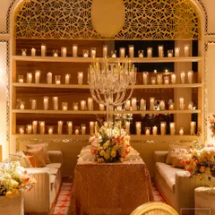 A cozy seating arrangement at the 'Sitara Mahal' dinner, with a crystal candelabra and a backdrop of countless candles. The design focused on creating a royal ambiance with ivory hues and intricate mirror work.