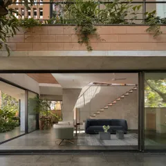 (Hero Media) This is our Debris Block House in Bangalore, where the ground floor opens completely to the landscape. We designed this to maximize the connection to the garden, with light streaming in from skylights and the multi-level open staircase, creating a seamless indoor-outdoor living experience.