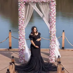 Our black off-the-shoulder mermaid gown is a client favorite. It offers a timeless, elegant look that beautifully accentuates the baby bump, perfect for both studio and outdoor settings.