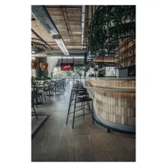 The long, curved bar is an understated focal point, clad in muted subway tiles and softly lit from below. As evening approaches, it becomes a glowing centerpiece that draws people together.