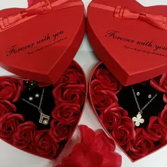 We have different necklace designs available in our heart-shaped gift boxes. Here you can see two options, one with a pearl and the other with a four-leaf clover design.