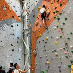 A new climber tackles one of our taller walls while his friend belays him from the ground. We teach you all the safety basics so you and your friends can support each other.
