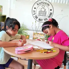 A moment of focused creativity. Two young artists are completely absorbed in their drawings, using markers and crayons to express their imagination during a summer workshop.
