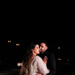A romantic night portrait of Priya and Kishan. The soft glow of the background lights creates a beautiful, intimate ambiance as they share a quiet embrace.