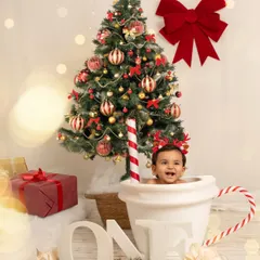 The same baby boy grins with delight from his hot chocolate mug prop, surrounded by presents and a beautifully decorated Christmas tree.