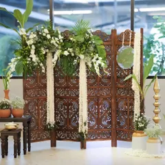 For a more traditional and earthy feel, I created this engagement backdrop using a carved wooden screen. The arrangement is enhanced with lush green foliage and cascades of white rajnigandha flowers.