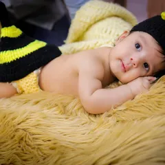A close-up of our adorable honeybee baby, awake and looking at the camera with big, curious eyes. The hand-knitted costume is soft and perfect for newborns.