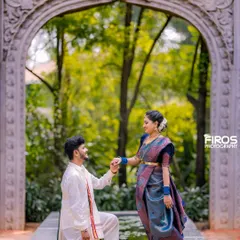 A classic proposal pose in traditional South Indian attire, set against a beautiful stone archway and pond.