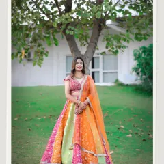 A beautiful solo portrait of the bride in her stunning, multi-colored lehenga. This shot highlights her grace and the beauty of her outfit against a simple, natural backdrop.