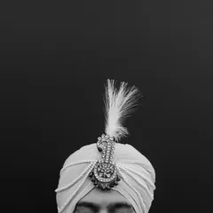 A minimalist black and white portrait focusing on the groom's turban (safa), highlighting a key element of his wedding attire.