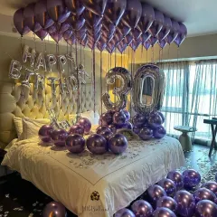 A sophisticated 30th birthday setup in a deep purple and silver color scheme. The metallic balloons add a touch of glamour, creating a mature and celebratory atmosphere in this hotel room decoration.
