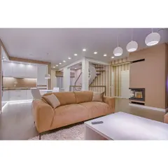 A warm and inviting living room with a comfortable brown sofa and modern spherical pendant lights. The design incorporates subtle LED strip lighting to highlight architectural details and create a cozy evening ambiance.