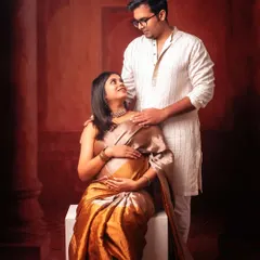 A classic fine-art maternity portrait featuring a couple in traditional Indian attire. The rich colors and elegant posing celebrate their cultural roots as they await their new arrival.