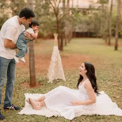 A playful moment on a picnic blanket. The natural, green background and relaxed poses create authentic and happy family portraits.