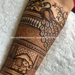 A classic bridal arm design starting with a majestic peacock surrounded by delicate branches. Below it, a decorated elephant adds a touch of royal procession to the artwork.