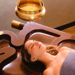 Experience the profound calm of Shirodhara, a timeless Ayurvedic therapy. A gentle, continuous stream of warm, herb-infused oil flows over your forehead, quieting the mind, soothing the nervous system, and restoring a sense of deep inner balance.