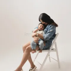 There is a universe of comfort in a mother's arms. This simple, elegant studio portrait shows a mother holding her son, their quiet connection and his happy smile being the central focus.