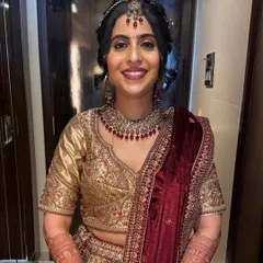 A full-length view of a smiling bride in her beautiful wedding lehenga. The complete look, including the elegant hairstyle and flawless makeup, was designed by our team to ensure she felt confident and looked stunning.