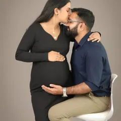 A truly intimate and loving moment. A husband-to-be kisses his wife's forehead as they both gently hold the baby bump, a beautiful expression of their shared journey.