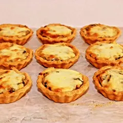 Savory mushroom tarts with a cheesy topping. These bite-sized quiches are a great vegetarian starter option for continental menus.